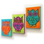 Three colorful owl paintings on a wall.