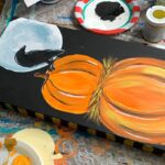 A Starry Night Kitty of a pumpkin and a crow on a table.