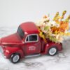 A red truck with flowers in it on a marble table.