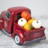 A red truck filled with pumpkins and gourds.