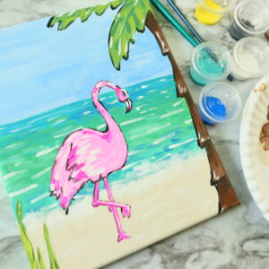 A painting of a pink flamingo on a beach.