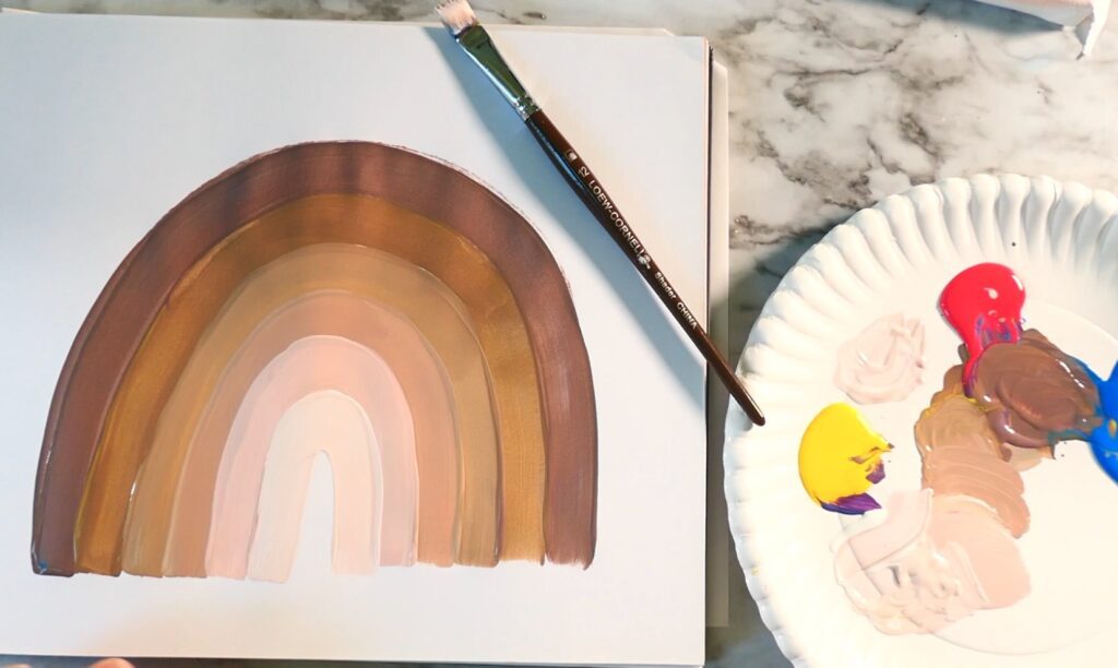 A person paints a rainbow on a piece of paper.
