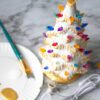 A "Natural" Ceramic Lit Christmas Tree Kit decorated with icing and paint on a table.