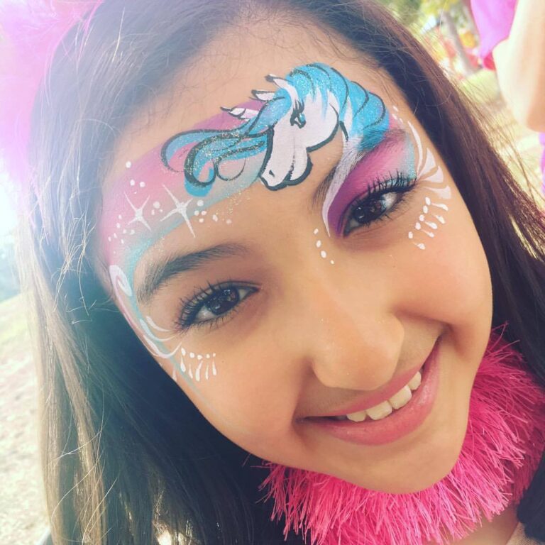 A girl with a unicorn face painted on her face at a party venue.
