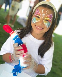 A young girl with face paint holding a toy.