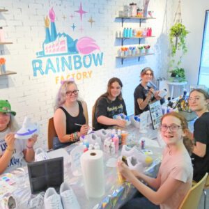 A group of people sitting at a table at a rainbow party.