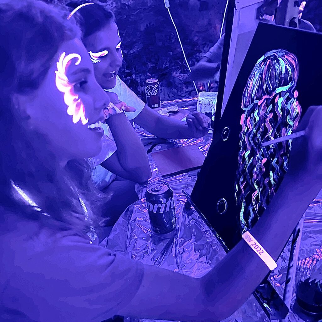 A group of people at a table painting with glow in the dark paint.