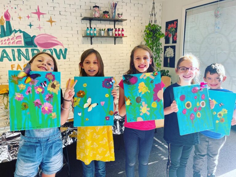 A group of kids holding up paintings in an art studio, perfect for art classes or camps.