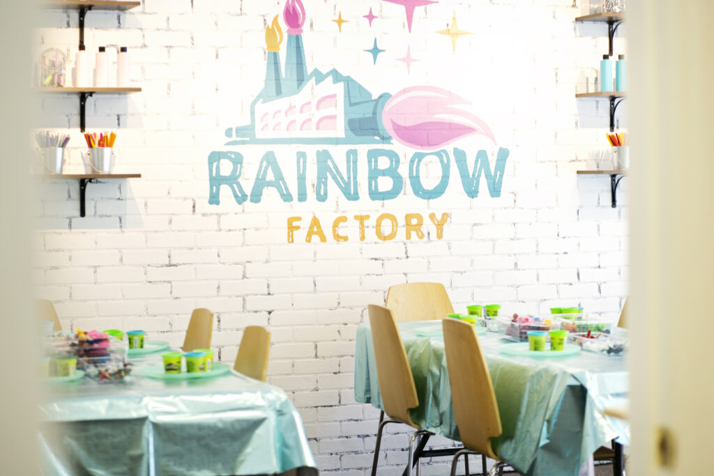 A room with tables and chairs and a sign that says rainbow factory.