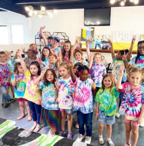 A group of children in tie dye shirts posing for a photo.