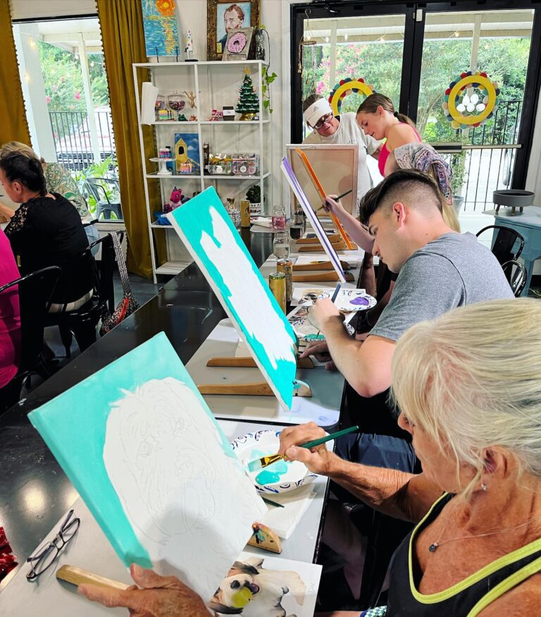A group of people painting at an art studio.