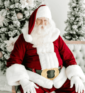 Santa claus sitting on a chair in front of christmas trees.