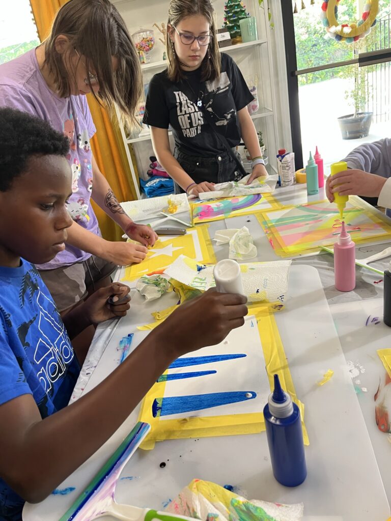 A group of people sitting around a table painting.