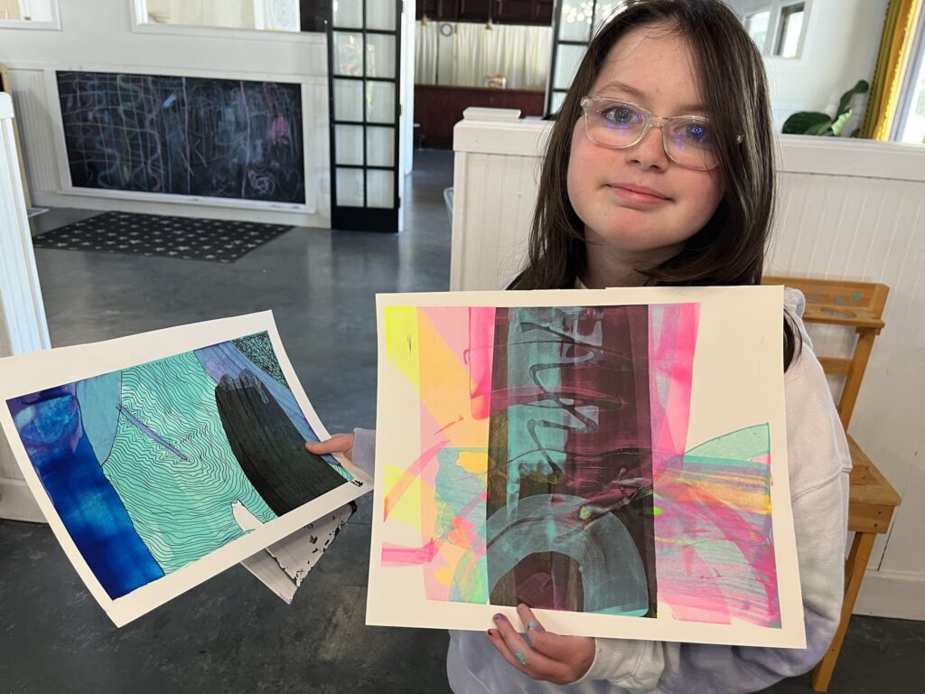 A girl holding two paintings of different shapes.