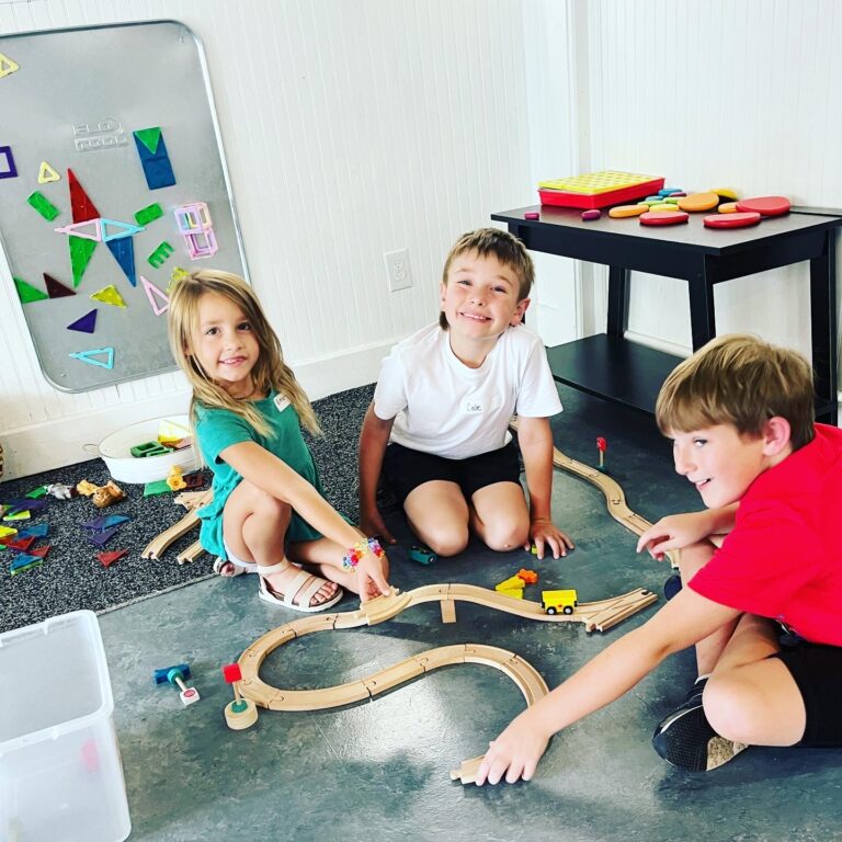 Three children playing with a toy train set.