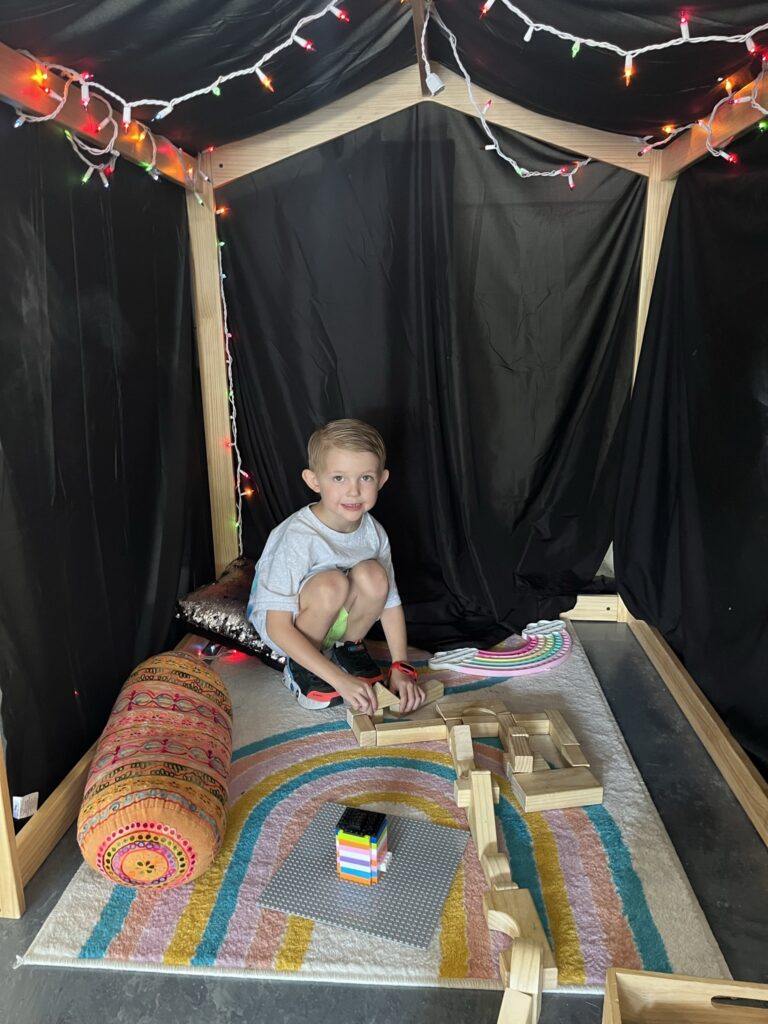 A boy sitting in the corner of a tent.