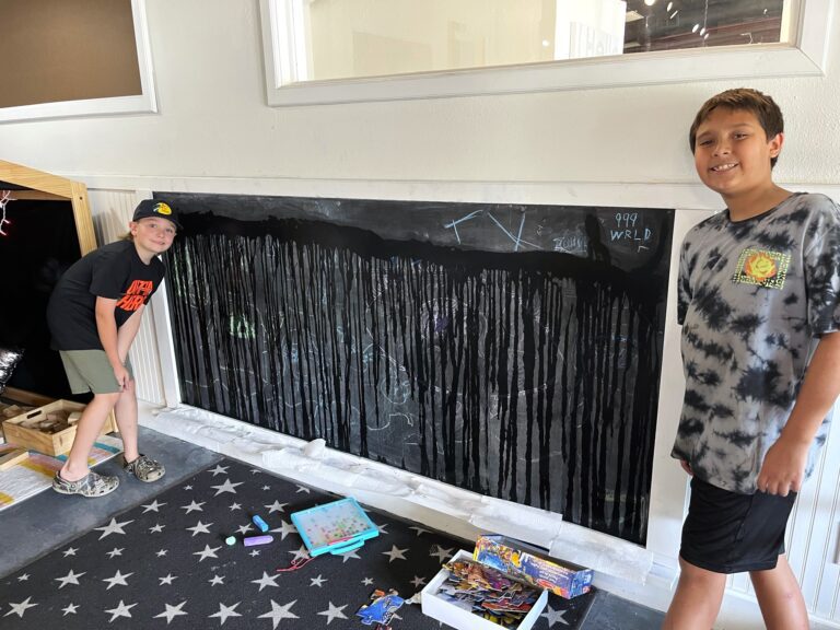 Two boys standing in front of a black wall.