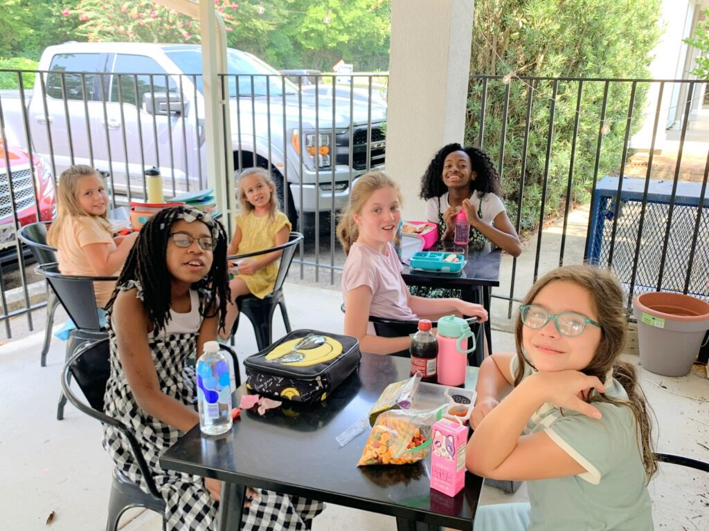 A group of girls sitting at a table with food.