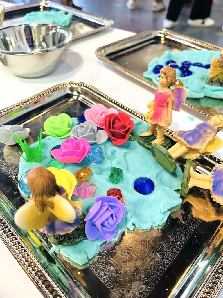 A table with two trays of colored sand and figurines.