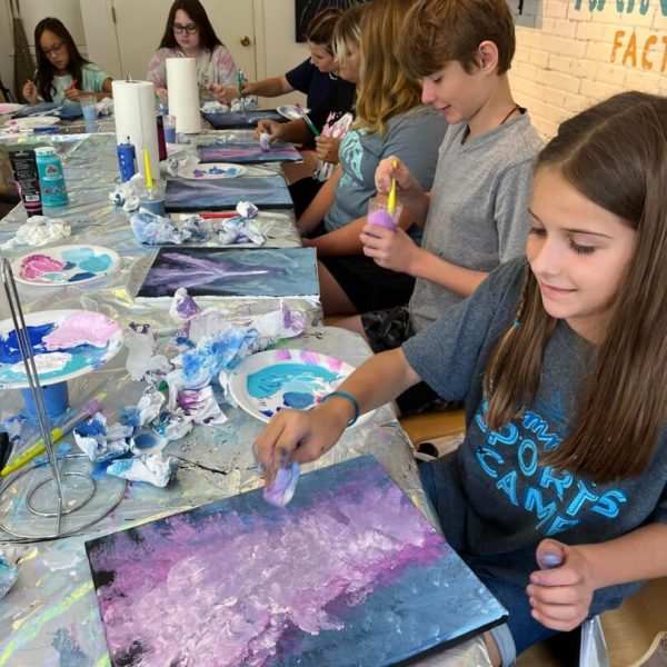 A group of young people painting at a table.