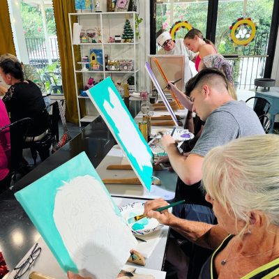 A group of people painting at an art studio.