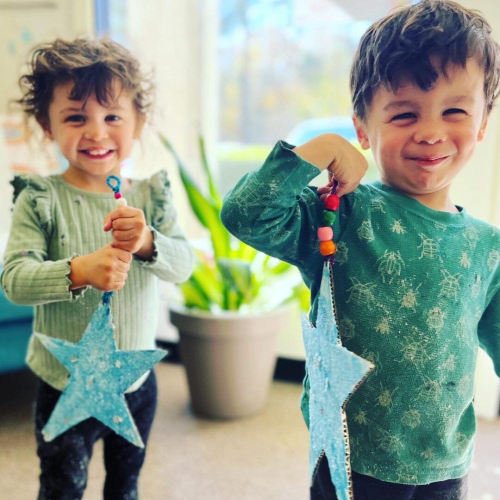 Two children holding star shaped decorations in a room.