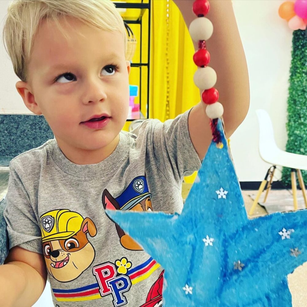 A young boy is playing with a star decoration.