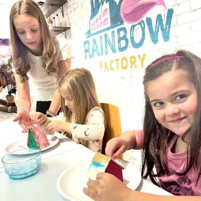 A group of girls at a table making crafts at the rainbow factory.