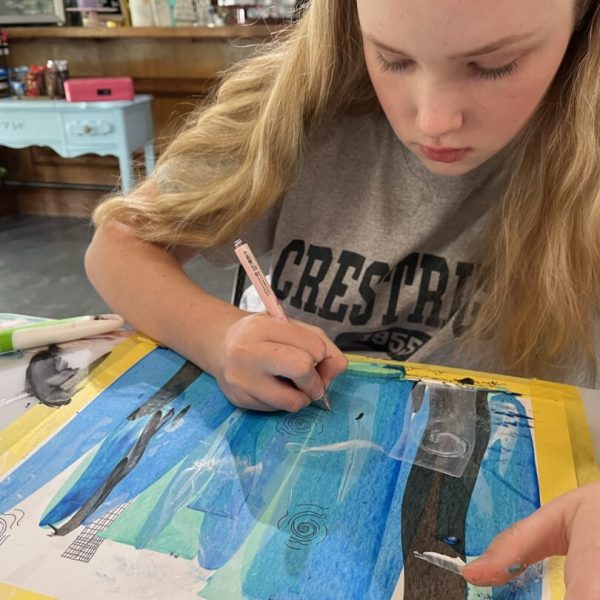 A girl is painting on paper with scissors.
