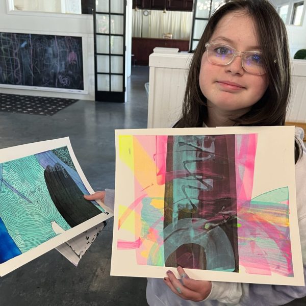 A girl holding two paintings of different shapes.