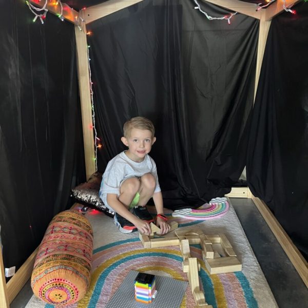 A boy sitting in the corner of a tent.