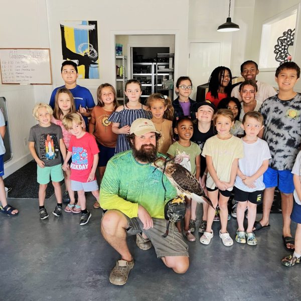 A group of people standing around a man holding an owl.