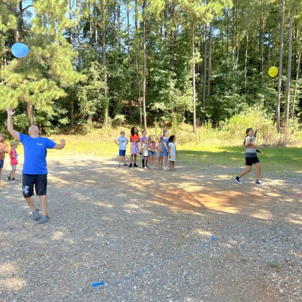 A group of people playing with balloons in the dirt.