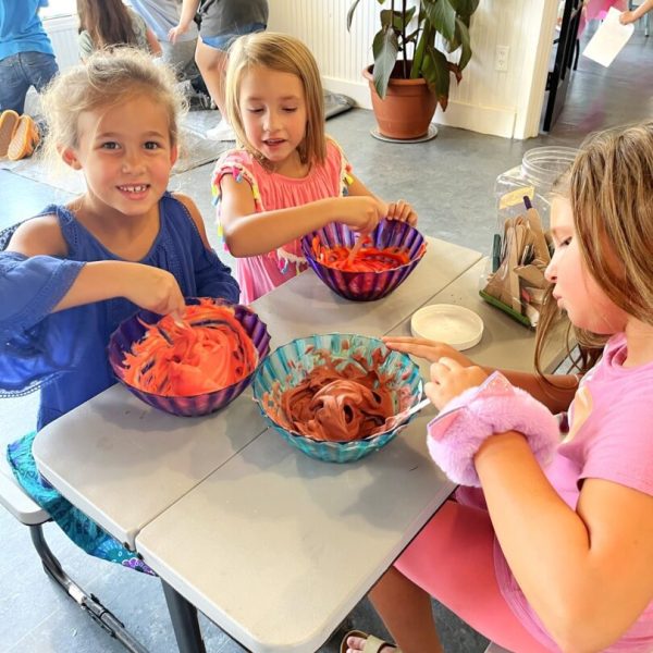 Three girls sitting at a table with bowls of food.