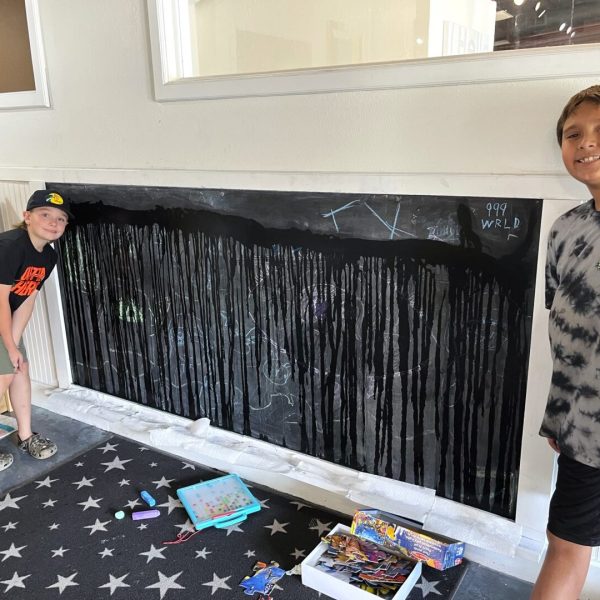 Two boys standing in front of a black wall.