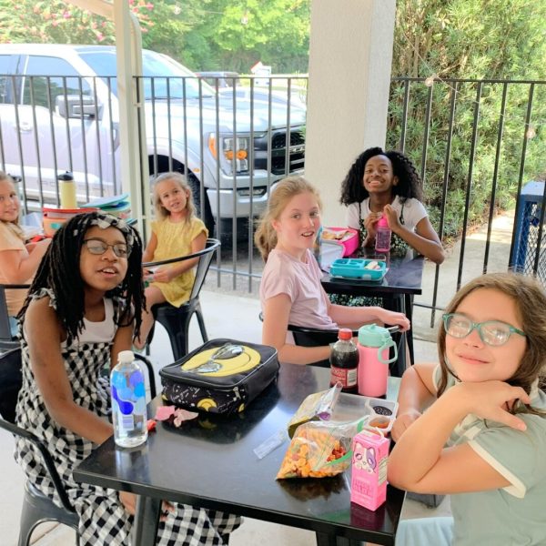 A group of girls sitting at a table with food.