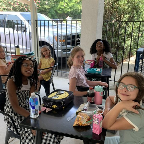 A group of girls sitting at a table with food.