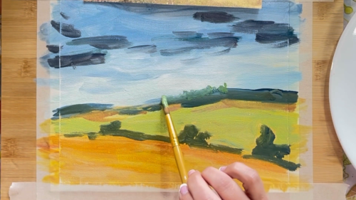 A person is painting a landscape on a piece of paper.